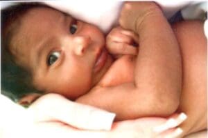 Baby wrapped in a white blanket, gazing.