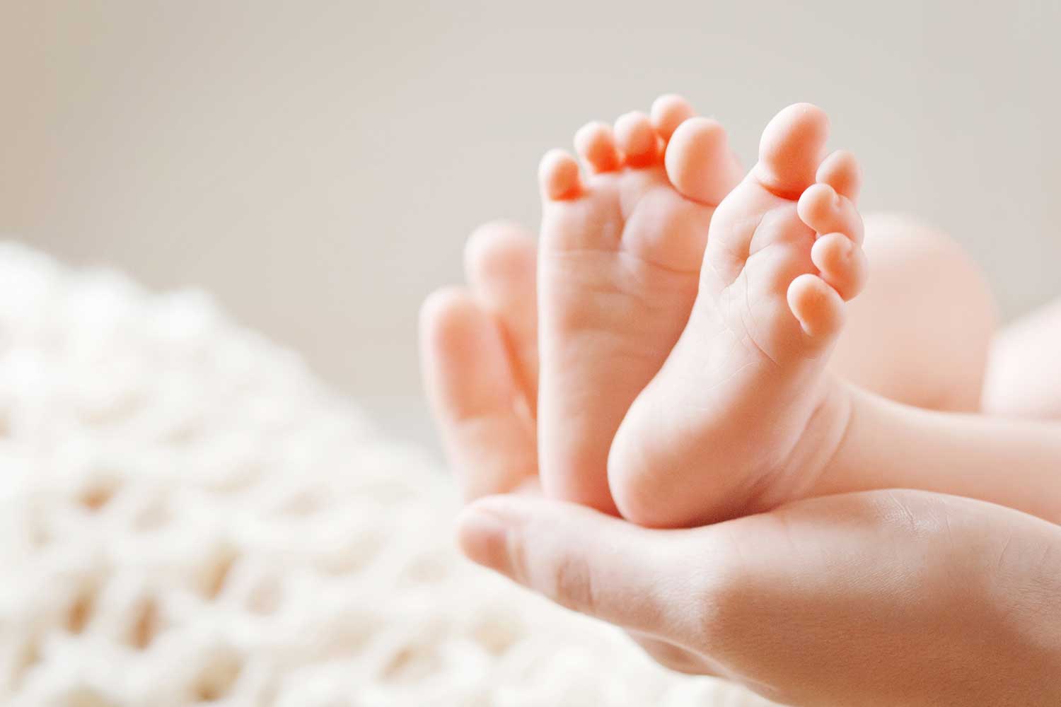 Baby feet held in gentle hands.