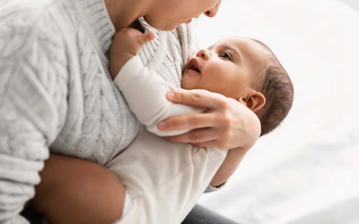 Adult holding and gazing at a baby.